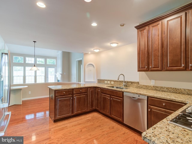 kitchen featuring kitchen peninsula, sink, hanging light fixtures, light stone countertops, and stainless steel appliances