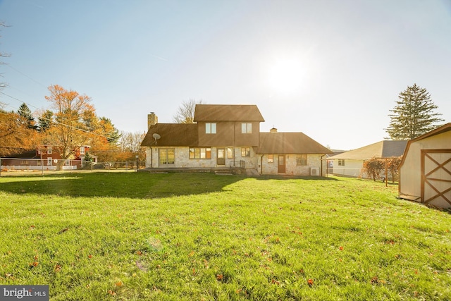 rear view of property with a lawn and a storage unit