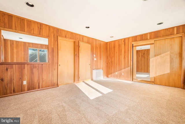 carpeted empty room featuring wood walls