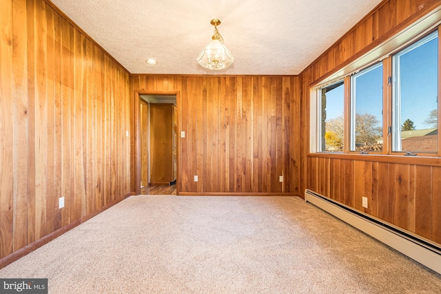 carpeted empty room featuring a baseboard heating unit, a notable chandelier, and a textured ceiling