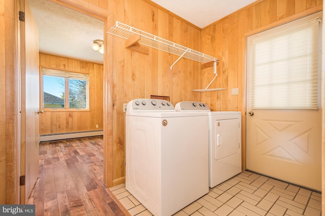 laundry area featuring a baseboard heating unit, independent washer and dryer, and wooden walls