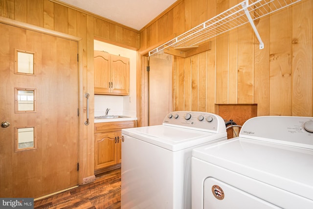 washroom with separate washer and dryer, sink, dark hardwood / wood-style floors, and wood walls