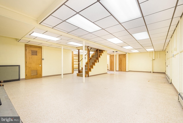 basement featuring a baseboard heating unit and a drop ceiling