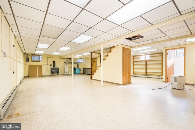 basement with water heater, a paneled ceiling, and a baseboard radiator