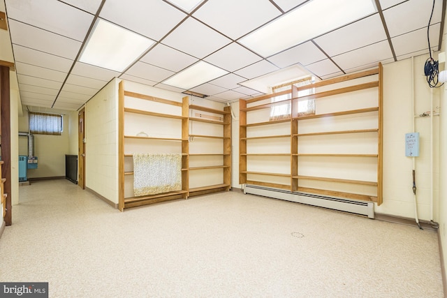 basement featuring a baseboard heating unit and a drop ceiling