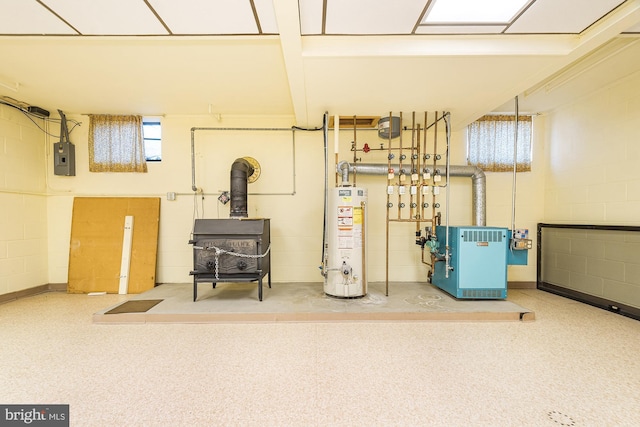 basement featuring electric panel, a wood stove, and gas water heater