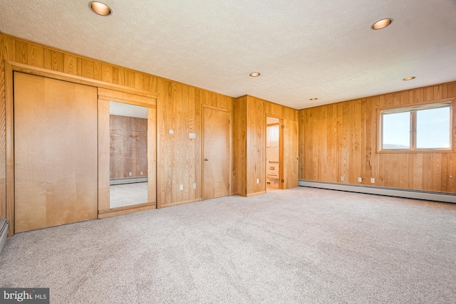 empty room featuring carpet flooring, a textured ceiling, and a baseboard radiator