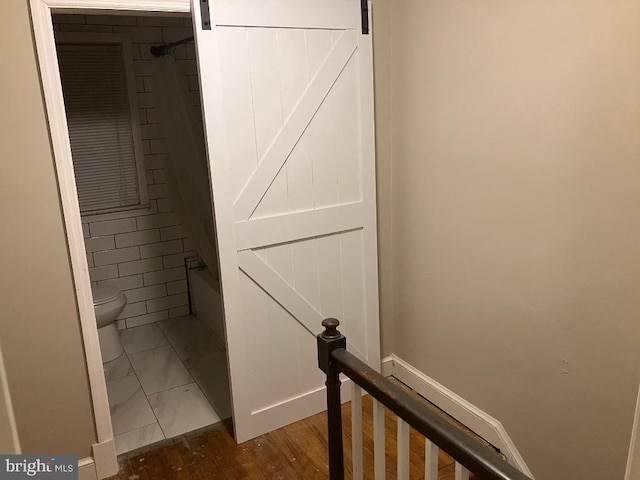 staircase featuring a barn door and tile patterned flooring