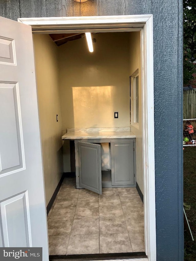 clothes washing area with ceiling fan and light tile patterned floors