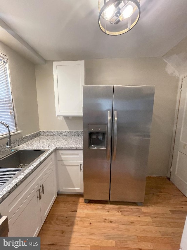 kitchen with white cabinets, stainless steel refrigerator with ice dispenser, sink, and light hardwood / wood-style flooring