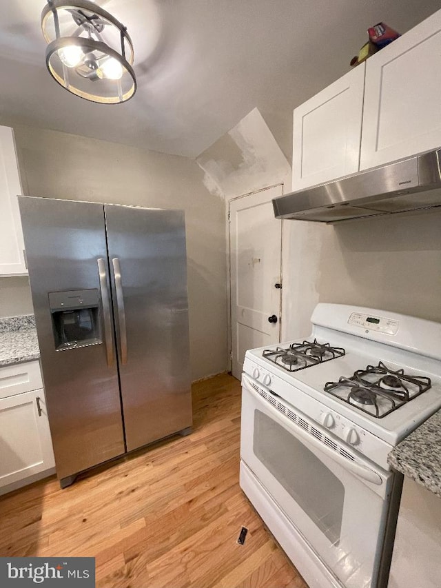 kitchen with white range with gas stovetop, stainless steel fridge, light wood-type flooring, white cabinets, and light stone counters