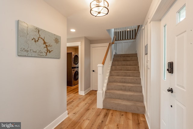 stairs with stacked washing maching and dryer and hardwood / wood-style flooring