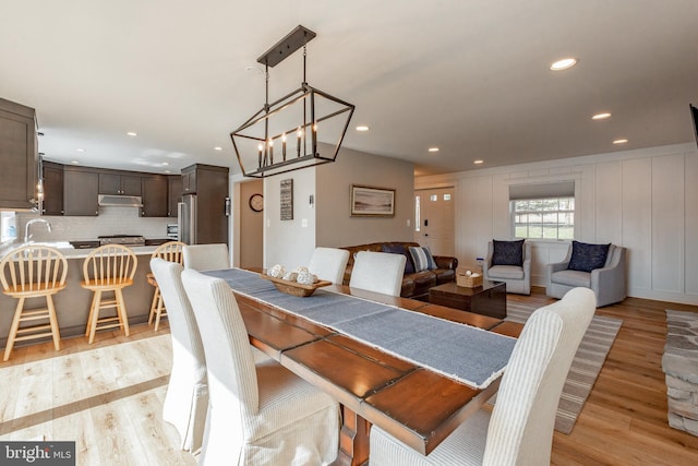 dining area with an inviting chandelier, light hardwood / wood-style floors, and sink