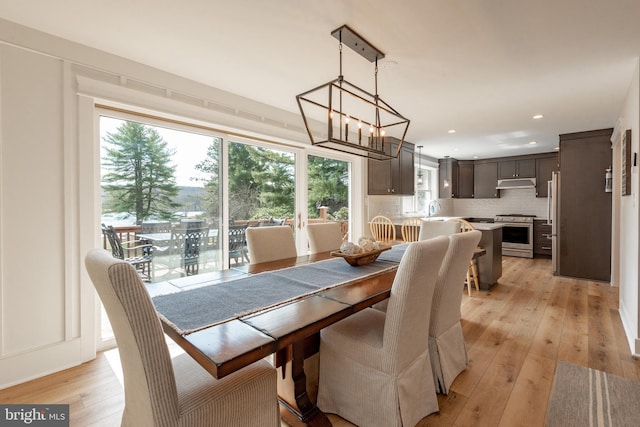 dining space featuring sink, light wood-type flooring, and an inviting chandelier