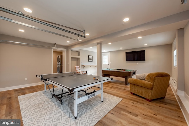 recreation room featuring stacked washing maching and dryer, light hardwood / wood-style floors, and billiards