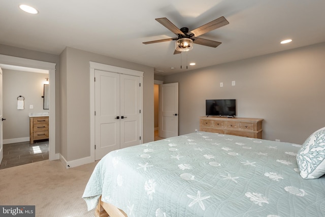 carpeted bedroom with ensuite bath, ceiling fan, and a closet