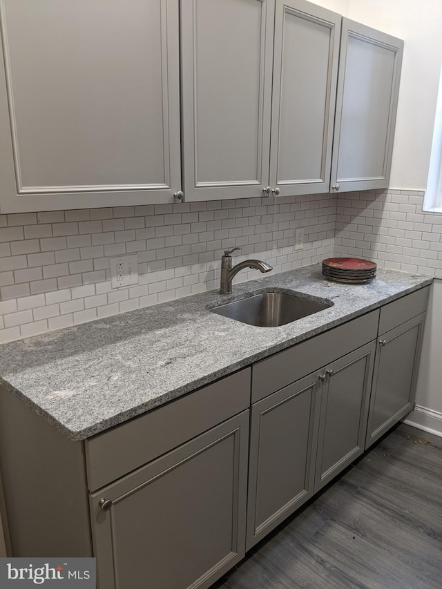 kitchen featuring hardwood / wood-style floors, gray cabinets, light stone countertops, and sink