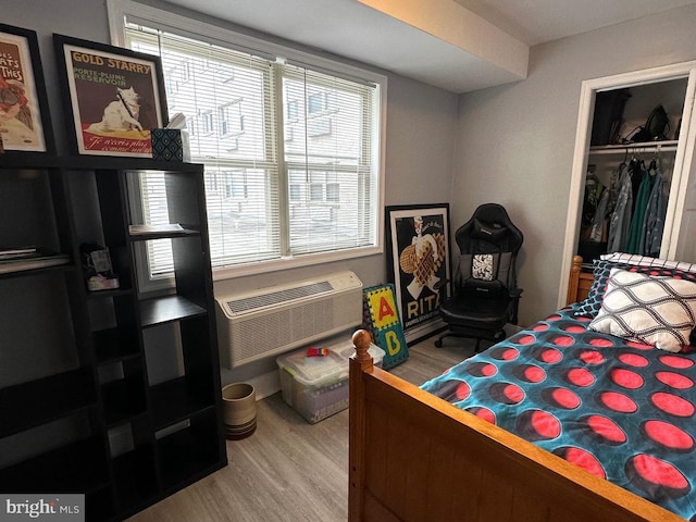 bedroom with a closet, hardwood / wood-style floors, and a wall mounted air conditioner