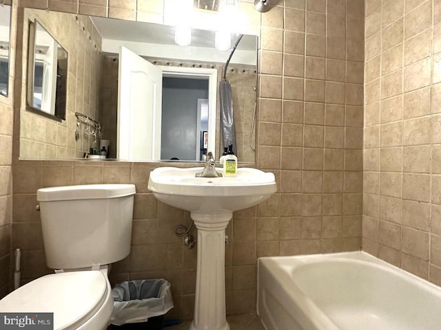 bathroom with toilet, tile walls, and bathing tub / shower combination