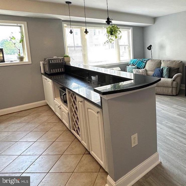 kitchen with a wealth of natural light, light tile patterned floors, and hanging light fixtures