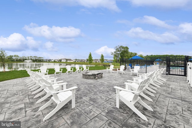 view of patio featuring a fenced in pool, a water view, and an outdoor fire pit