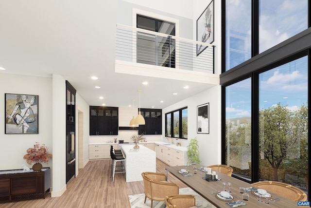 dining room featuring sink, light hardwood / wood-style floors, and a high ceiling