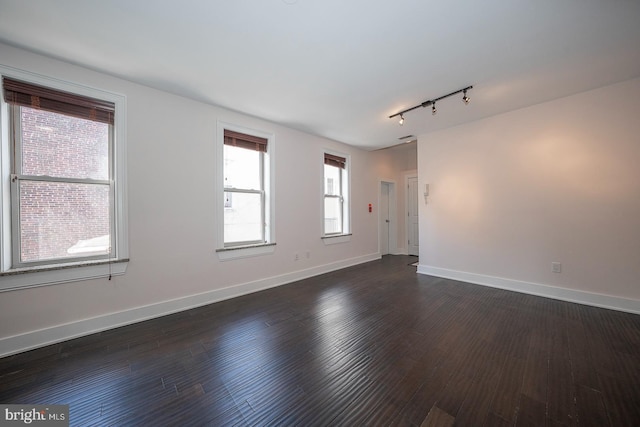 empty room featuring dark hardwood / wood-style flooring and rail lighting