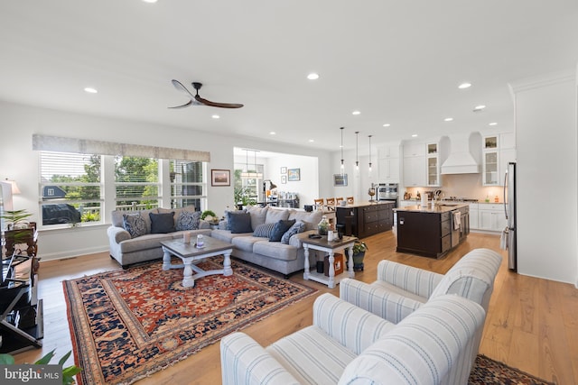 living room with light hardwood / wood-style floors, sink, and ceiling fan