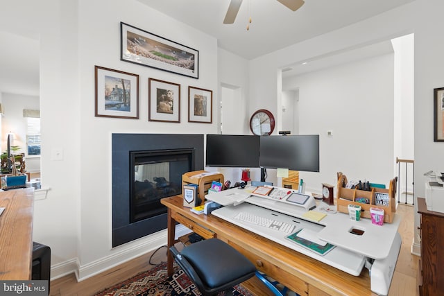 office space with hardwood / wood-style floors, a multi sided fireplace, and ceiling fan