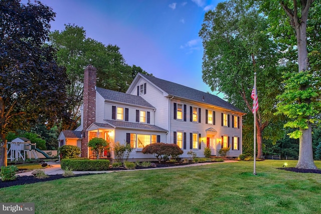 colonial home featuring a playground and a lawn