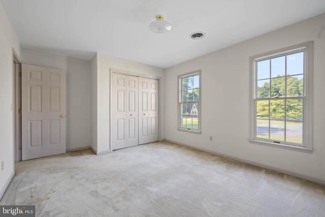 unfurnished bedroom with light colored carpet and a closet