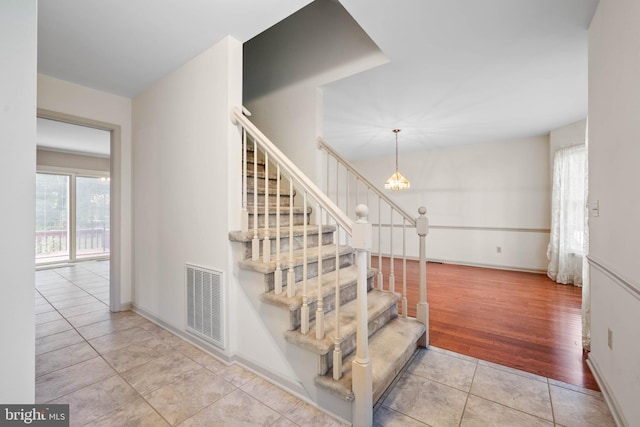 stairway featuring a notable chandelier and light tile patterned floors