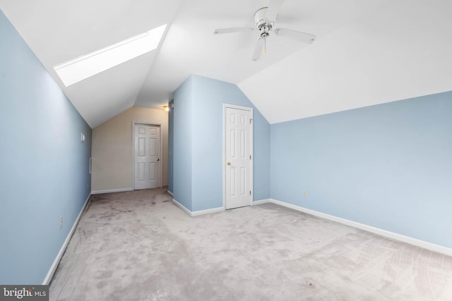 additional living space with lofted ceiling with skylight, carpet, and ceiling fan