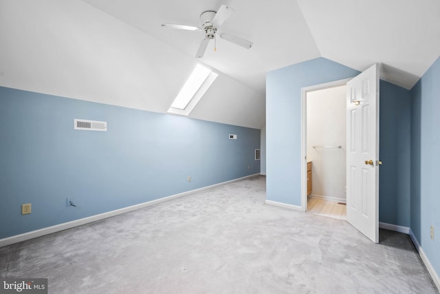 additional living space with light carpet, vaulted ceiling with skylight, and ceiling fan