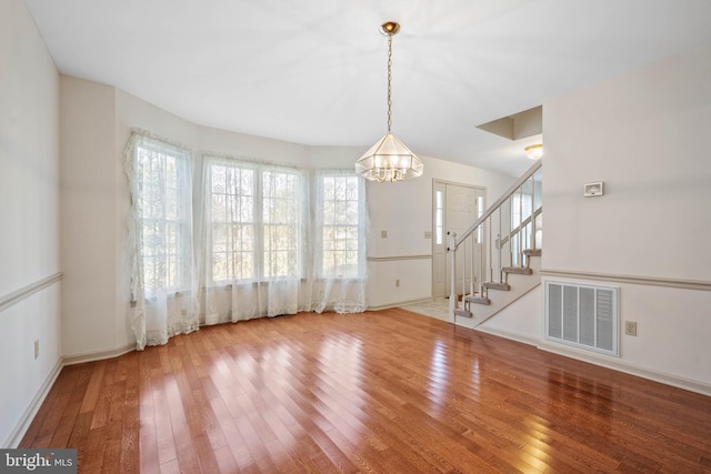 unfurnished dining area with plenty of natural light, a chandelier, and light hardwood / wood-style floors