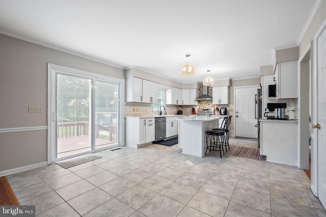 kitchen featuring wall chimney range hood, backsplash, decorative light fixtures, a kitchen island, and dishwasher