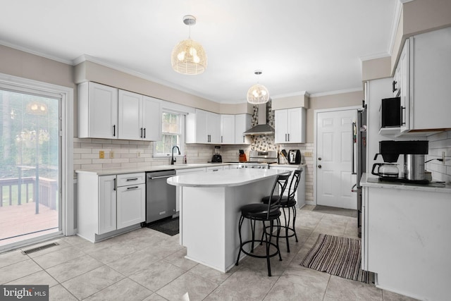 kitchen featuring white cabinetry, wall chimney range hood, dishwasher, hanging light fixtures, and decorative backsplash