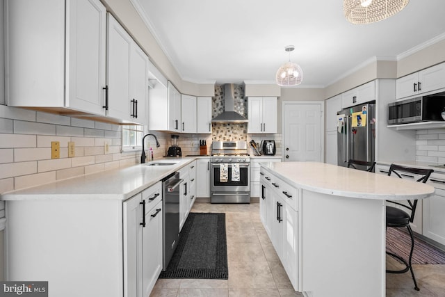 kitchen with stainless steel appliances, wall chimney exhaust hood, sink, a kitchen island, and backsplash