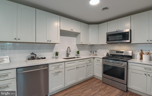 kitchen featuring sink, decorative backsplash, light wood-type flooring, and stainless steel appliances