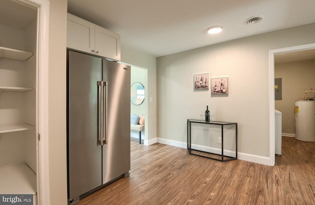 interior space with white cabinetry, light wood-type flooring, electric panel, electric water heater, and high end refrigerator