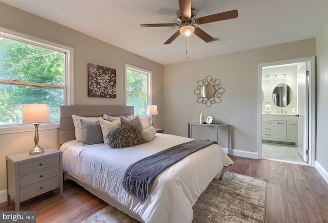 bedroom with ensuite bathroom, ceiling fan, and dark wood-type flooring