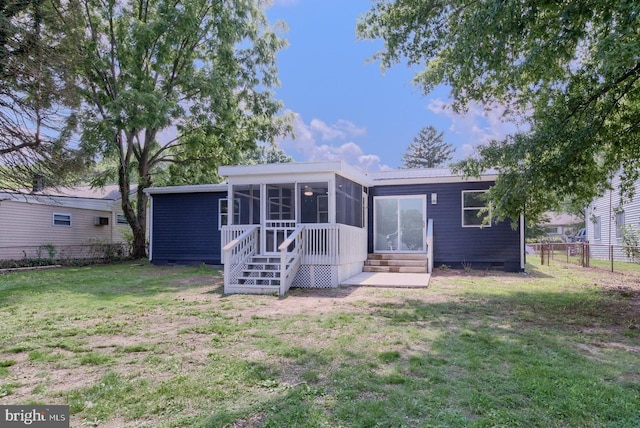 rear view of house featuring a sunroom and a lawn