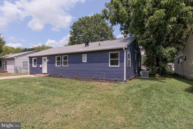 rear view of property featuring central AC and a yard