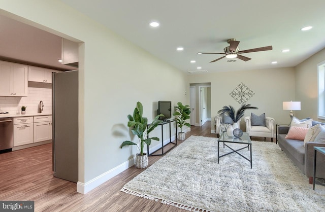 living room with light hardwood / wood-style floors, sink, and ceiling fan