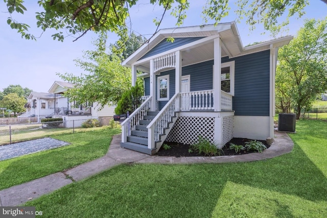 view of front facade featuring central AC, covered porch, and a front yard