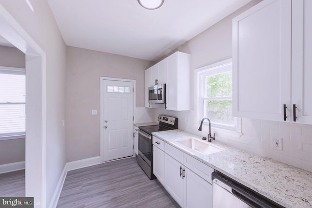 kitchen featuring light stone countertops, sink, stainless steel appliances, decorative backsplash, and white cabinets