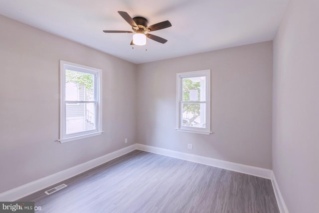 empty room with ceiling fan, wood-type flooring, and a wealth of natural light