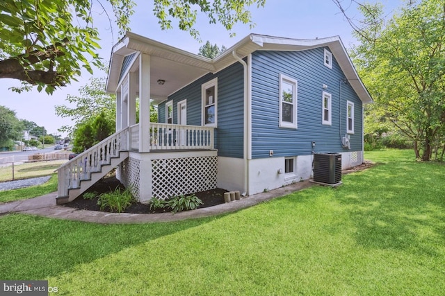 view of side of property with covered porch, a yard, and central air condition unit