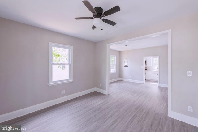 spare room featuring ceiling fan, a healthy amount of sunlight, and light hardwood / wood-style floors