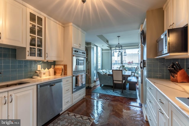 kitchen featuring backsplash, decorative light fixtures, white cabinetry, and stainless steel appliances